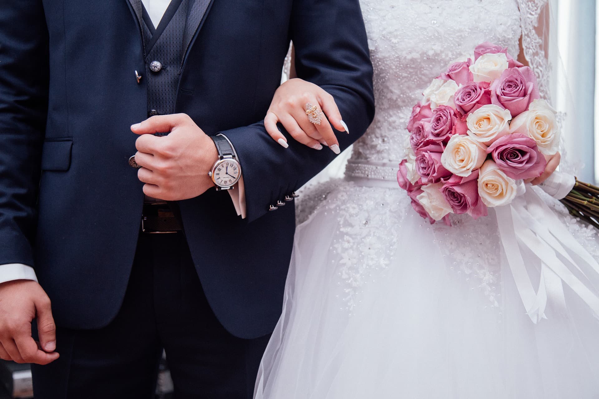 Bruidspaar arm in arm met rozenboeket na de ceremonie