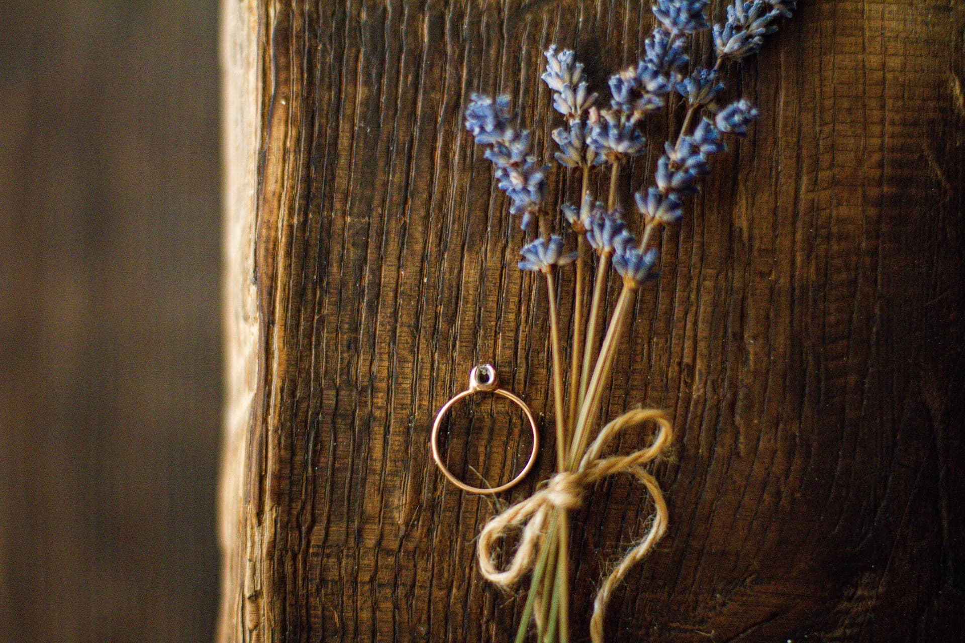 Gouden ring naast een bosje gedroogde lavendel met touwtje op een houten plank