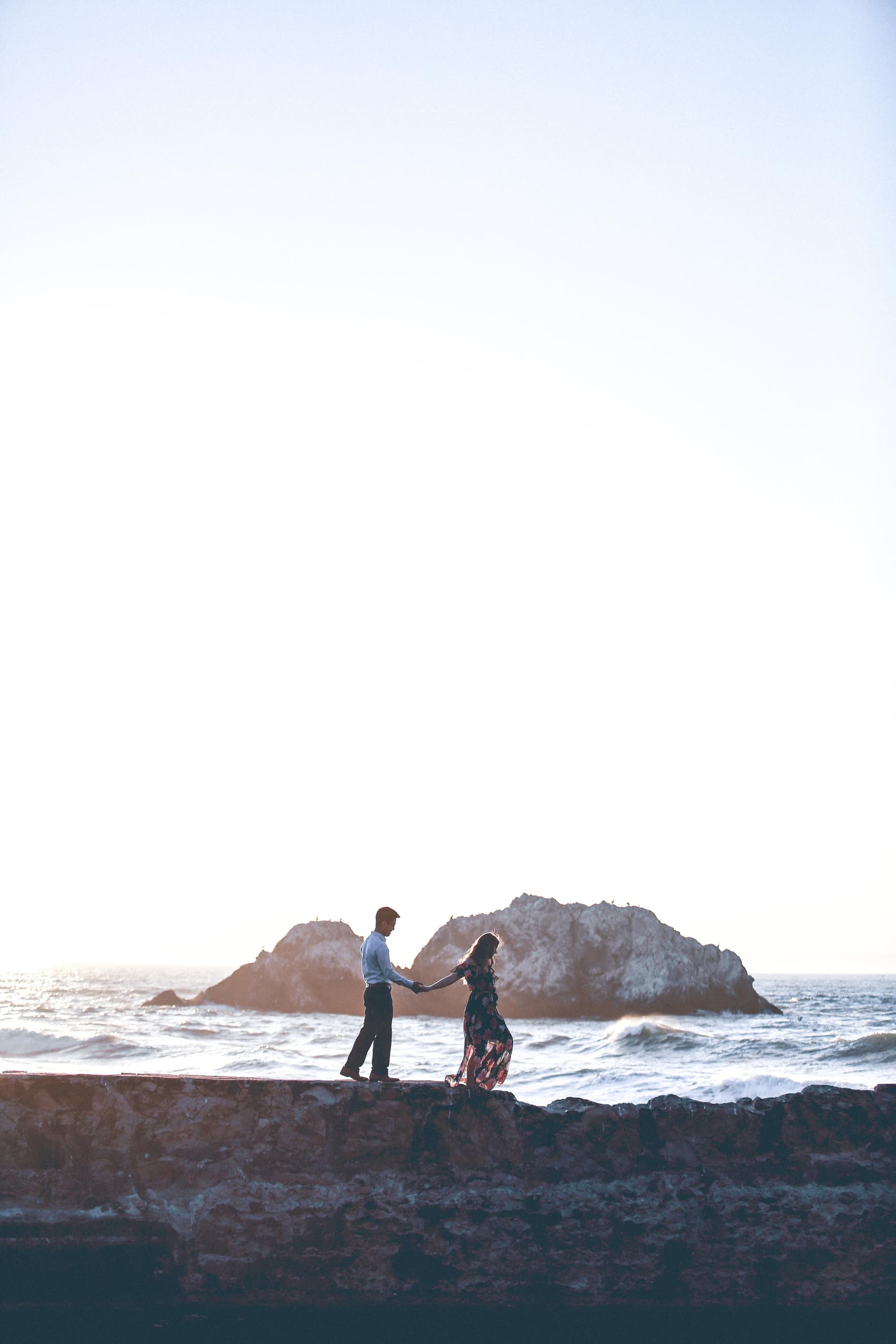 Koppel wandelt hand in hand langs de kust tijdens golden hour
